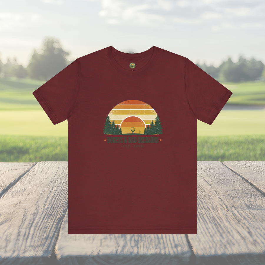 Maroon t-shirt with a sunset and tree graphic on a wooden surface with a natural background